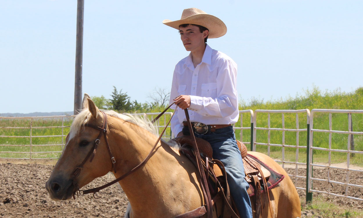Frank Huber riding a tan horse in a corral.