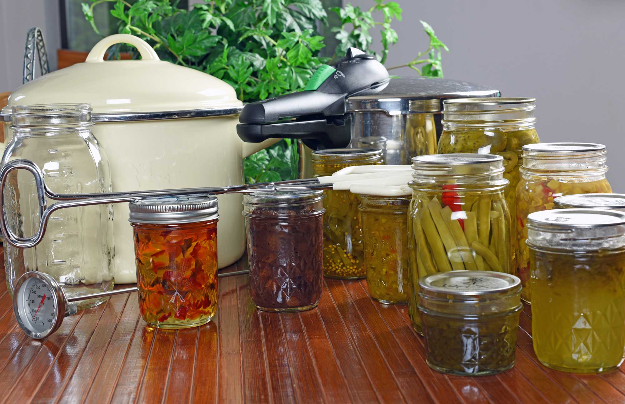 Home canning supplies and canned vegetables arranged on a countertop.