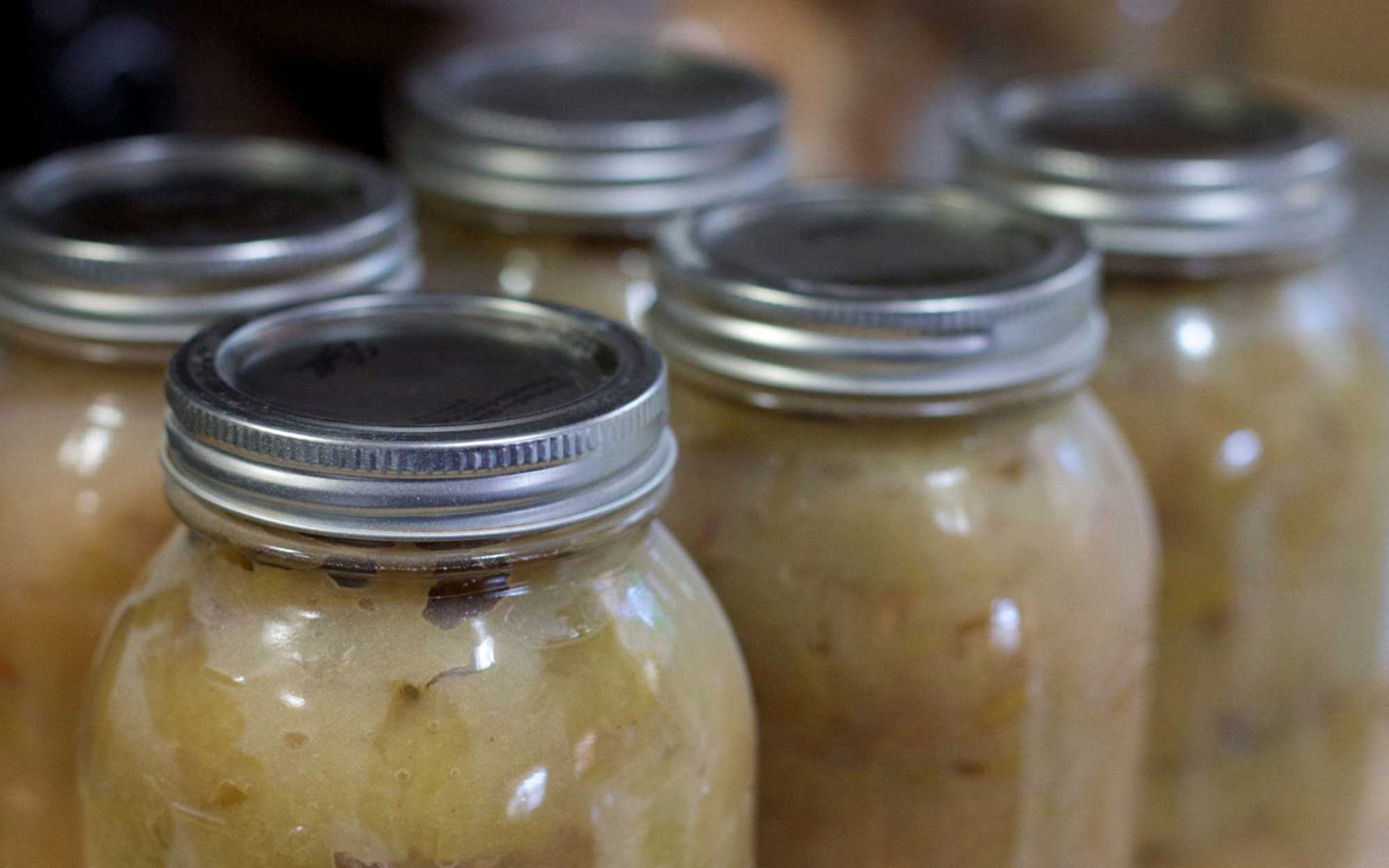 Several cans of homemade applesauce on a countertop.