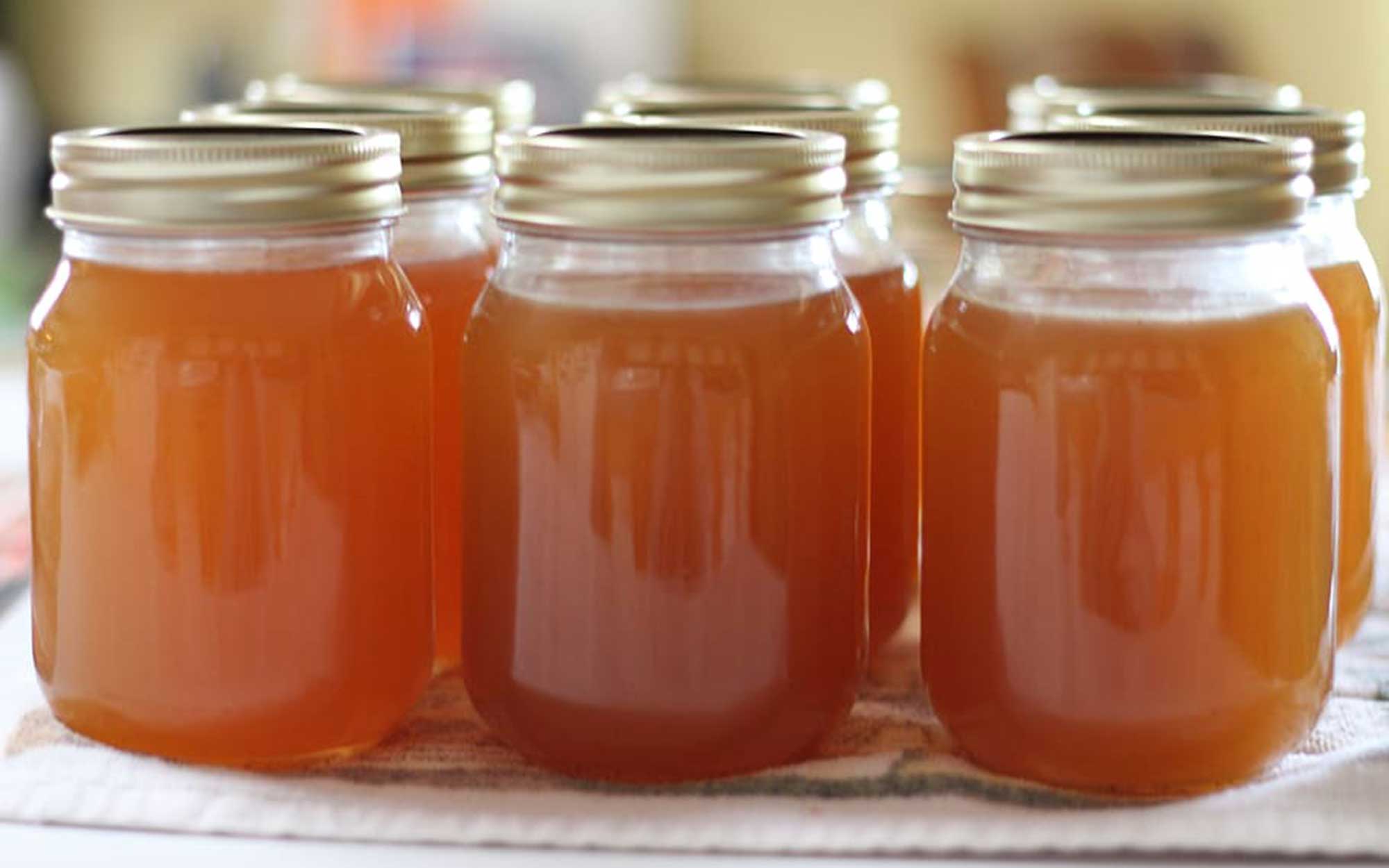 Six jars of reduced-sugar apple jelly on a counter.