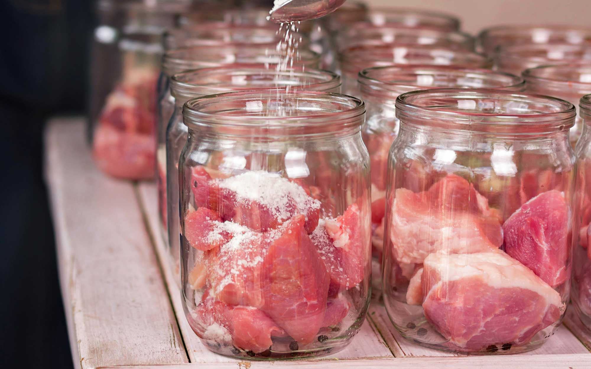 Several jars of meat being prepared for home canning.