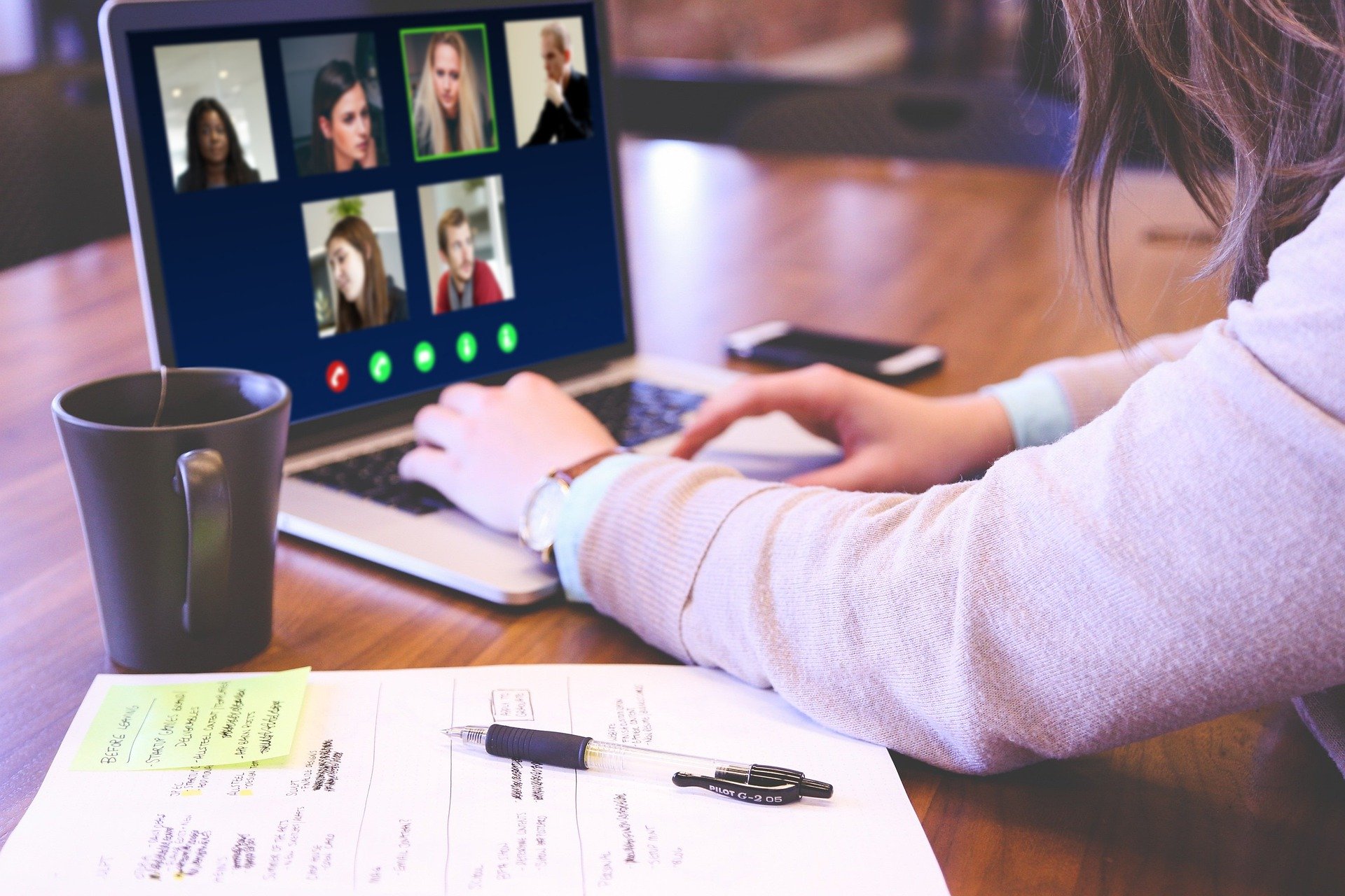 a woman using a laptop to join a video meeting with other people