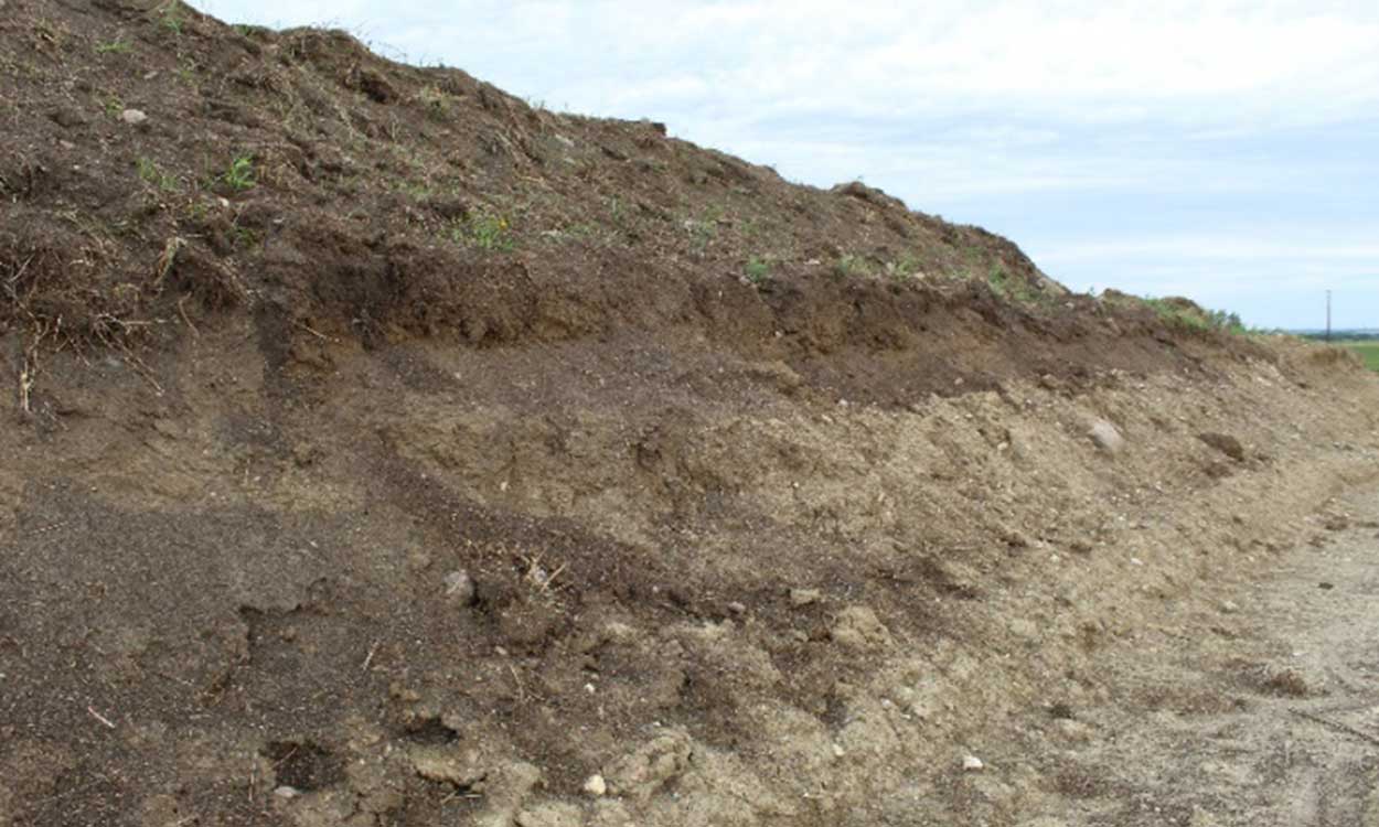 A large, dirt ridge near a service road for a wind energy station.