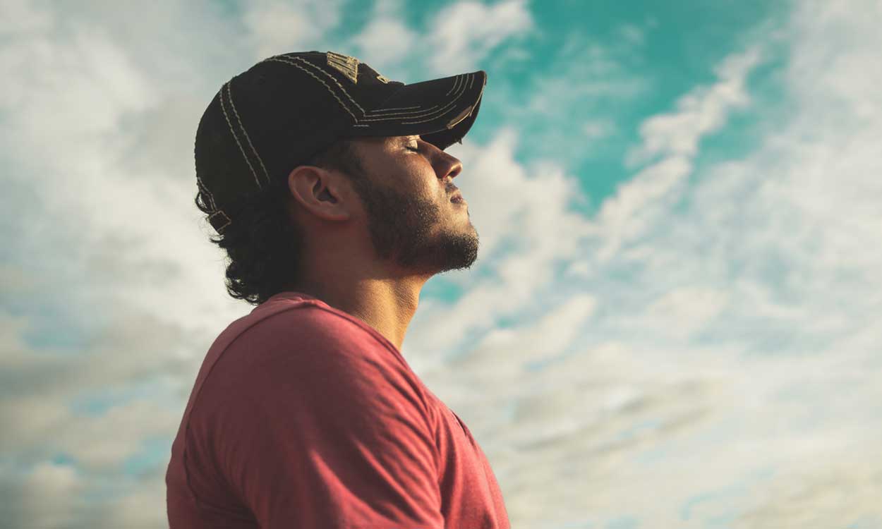 A young man with his eyes closed focusing on his breath.