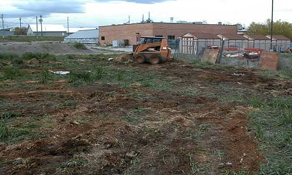 Skidloader outside being used to turn compost pile.