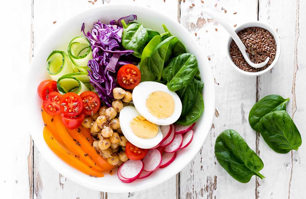 A salad bowl filled with a variety of fresh vegetables and slived eggs.