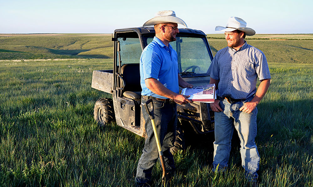 Two ranchers in a pasture reviewing a mangement plan.