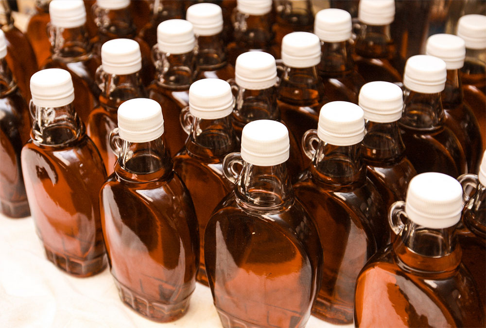 Bottles of maple syrup arranged on a table.