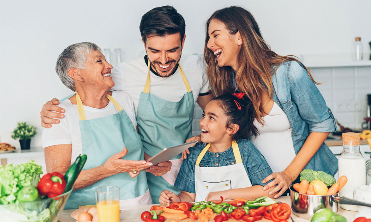 Grandmother, parents, and daughter preparing vegetables in a kitchen.