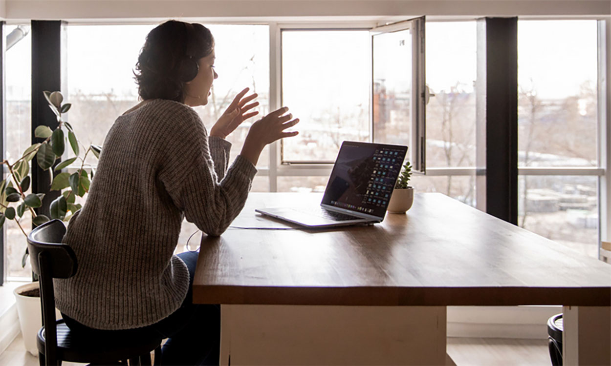 Young woman participating in a video conference at a remote work station.