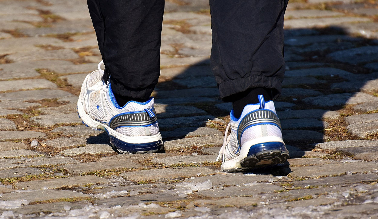 Person walking outdoors wearing a pair of comfortable walking shoes.