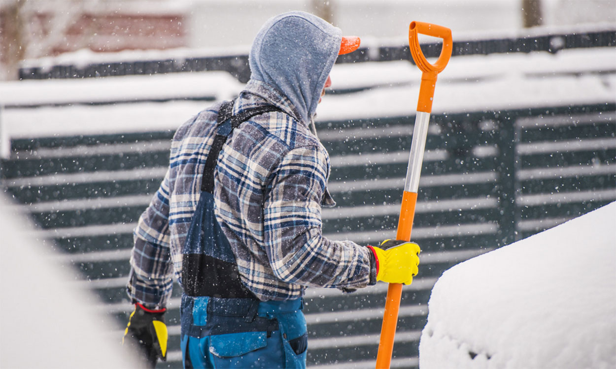 Dairy employee in winter clothing holding a shovel.