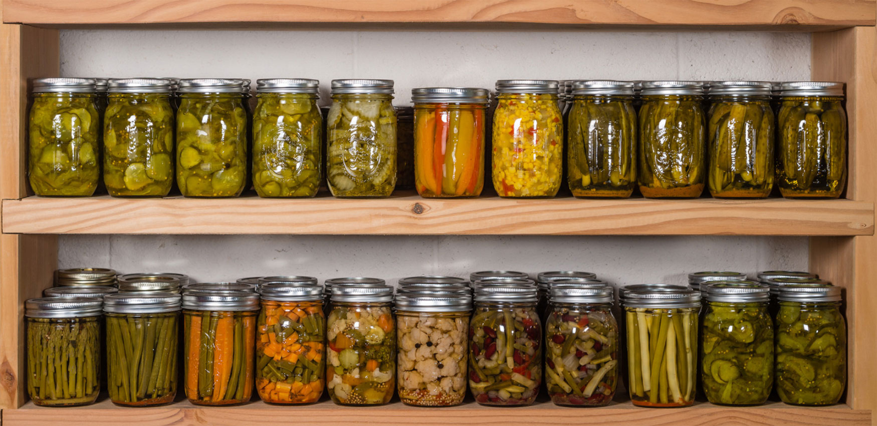 Several jars of home-canned vegetables arranged on a shelf.