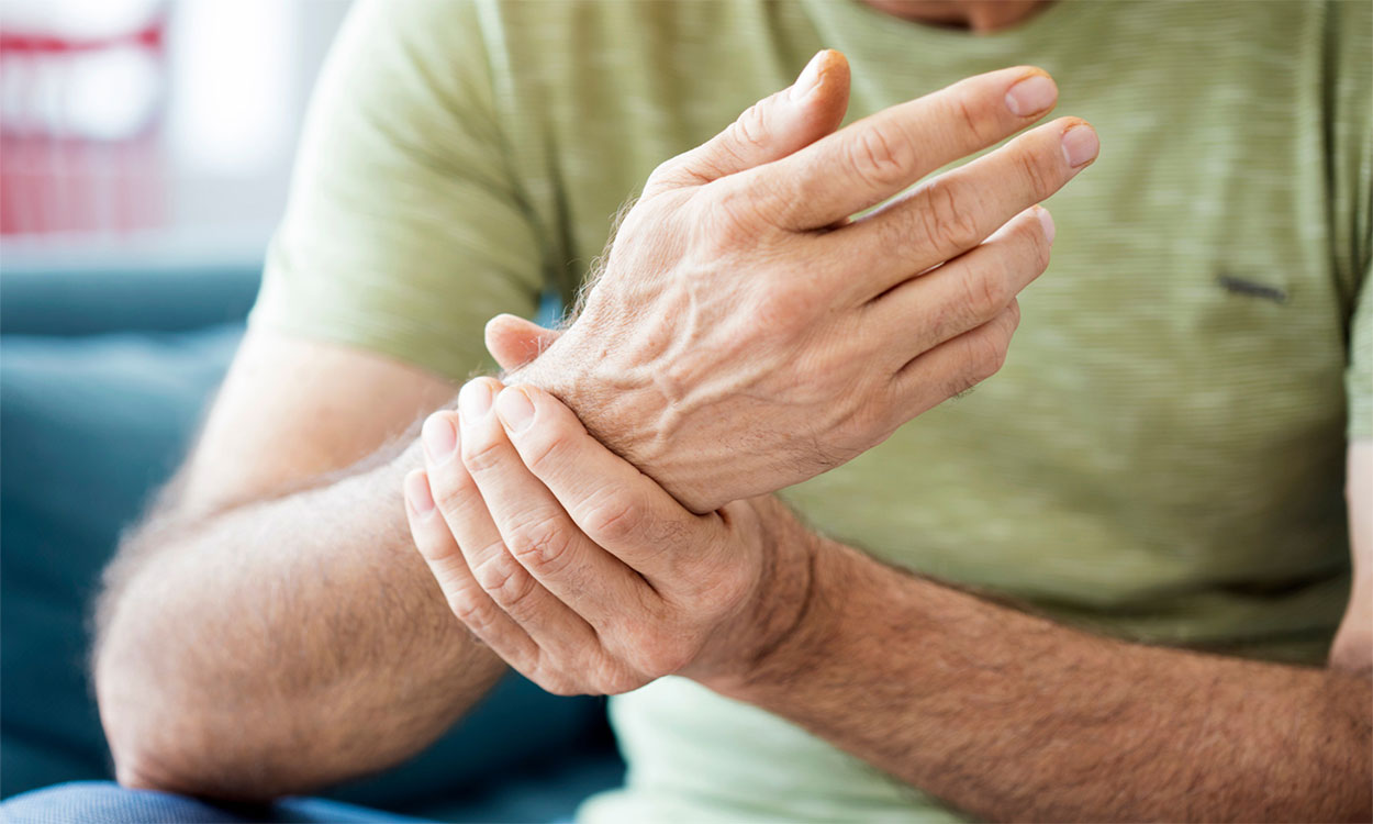 Man holding his wrist, which is afflicted with arthritis.