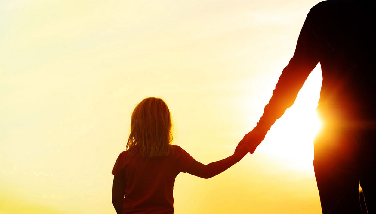 Silhoutte of mother and daughter holding hands at sunset.