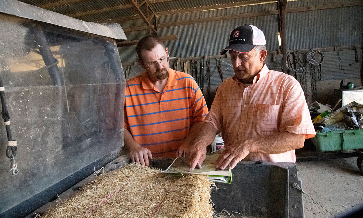 Landowner and producer in a machine shed reviewing a contract.