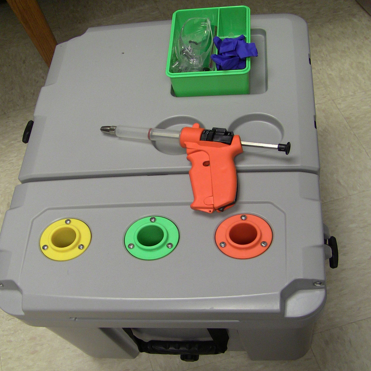Heavy-duty cooler with color-coded slots for vaccines and a compartment for syringe and supplies.
