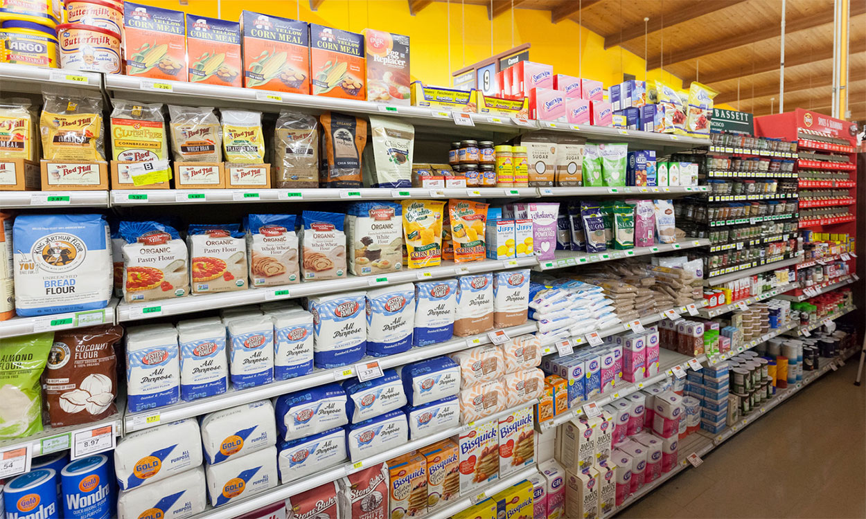 Variety of flour types on display in a grocery aisle.