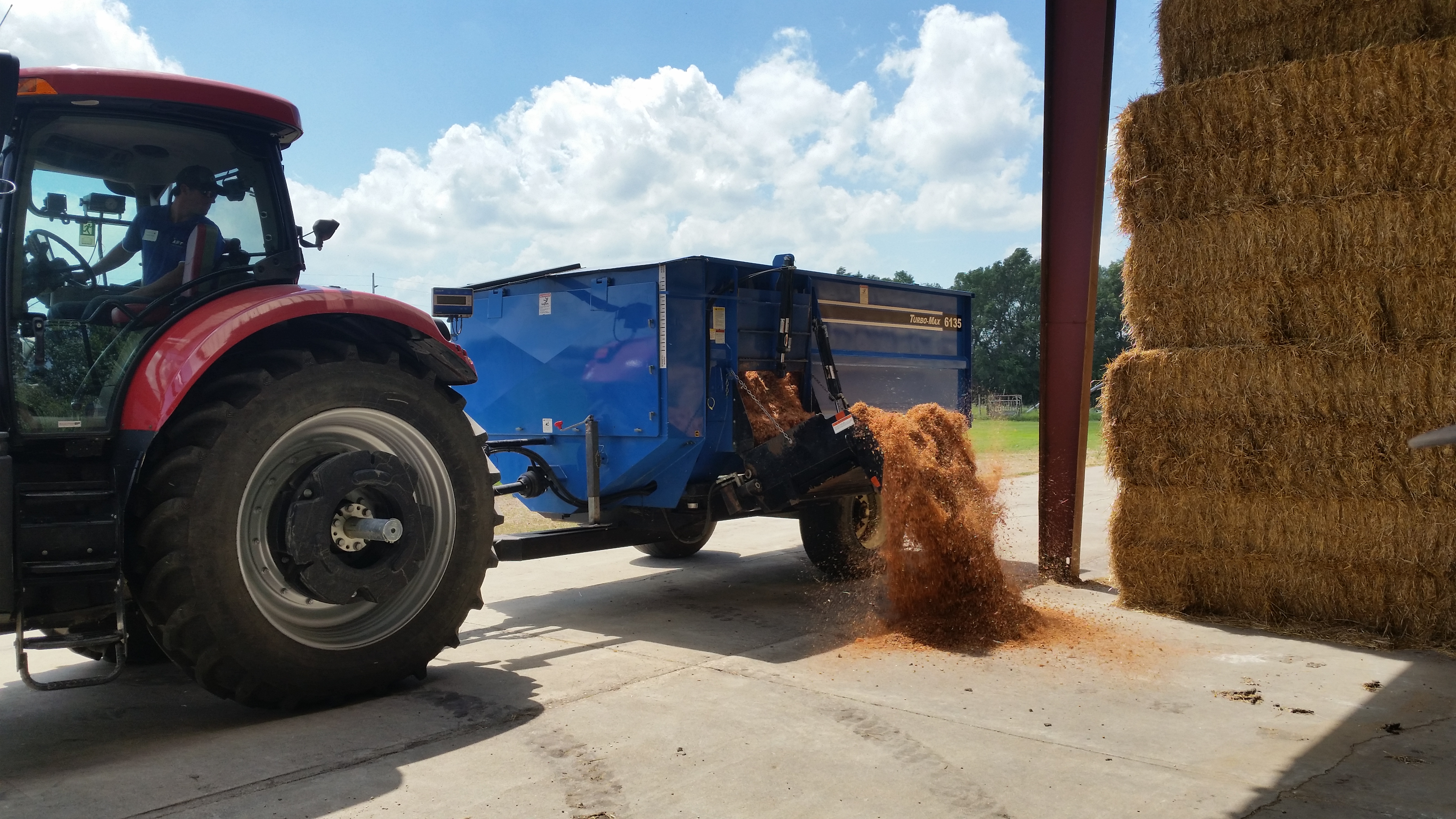 a tractor pulling a blue feed wagon