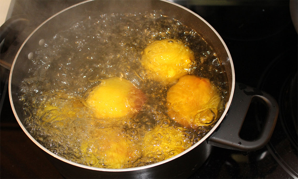 Several peaches submerged in boiling water.