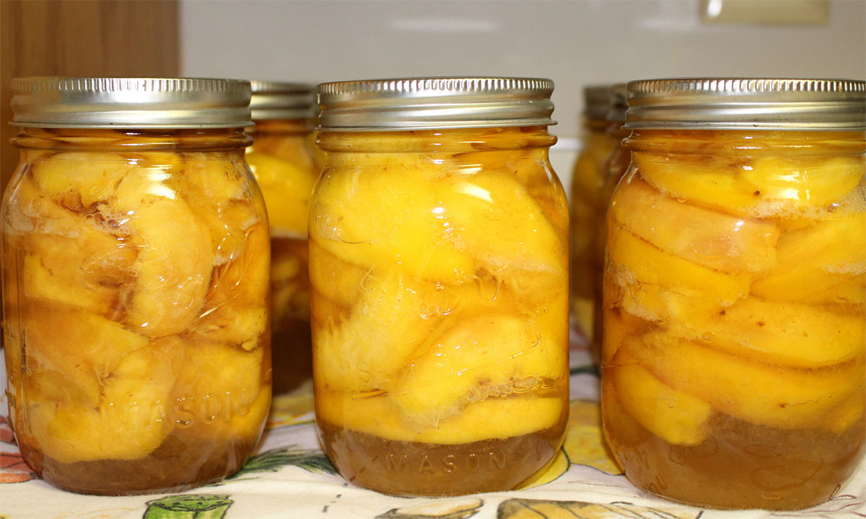 Several jars of canned peaches arranged on a countertop.