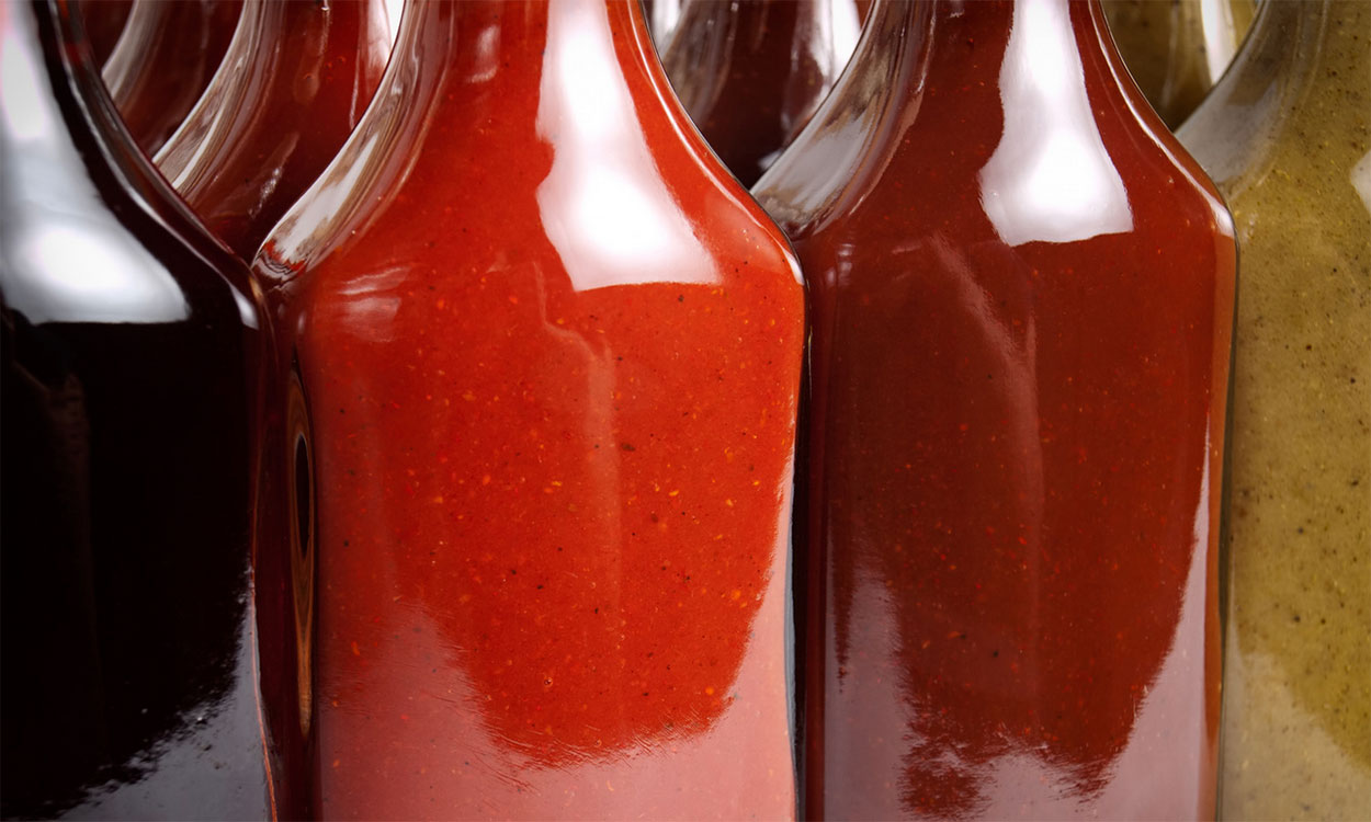 Several bottles of different hot sauces arranged on a counter.