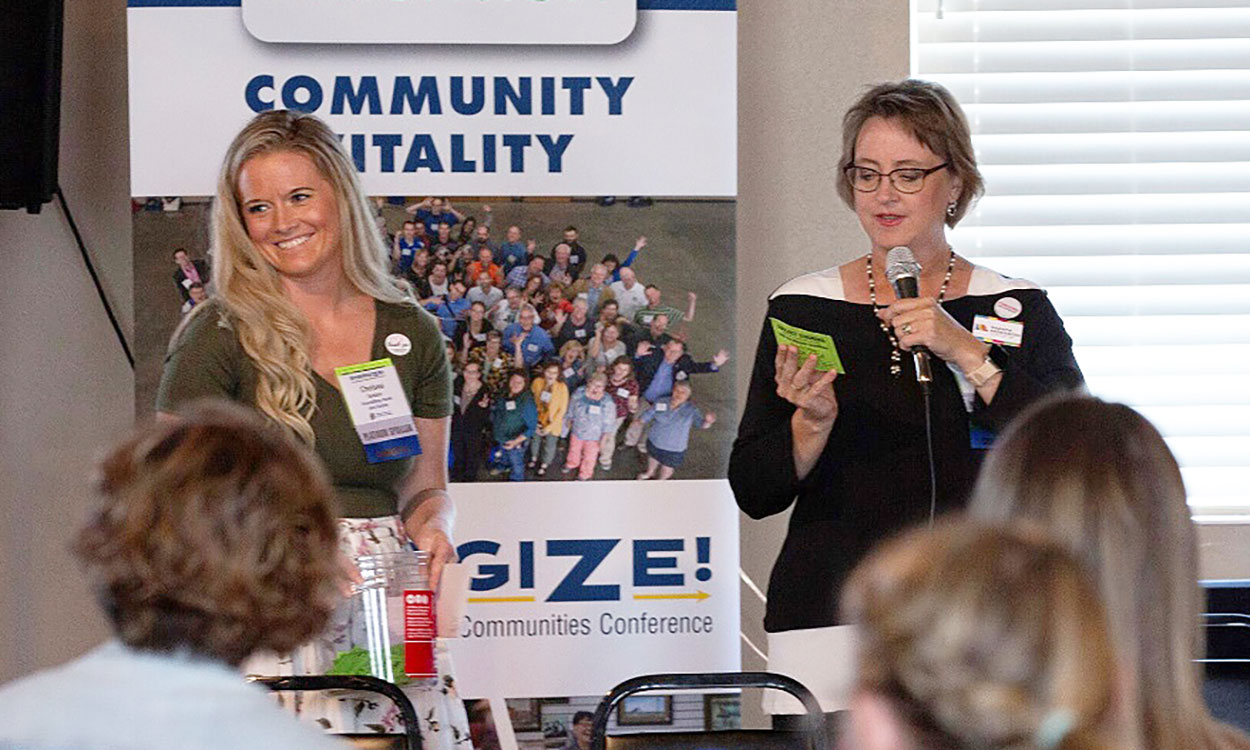 Two women announcing winners of a drawing at the Energize conference.