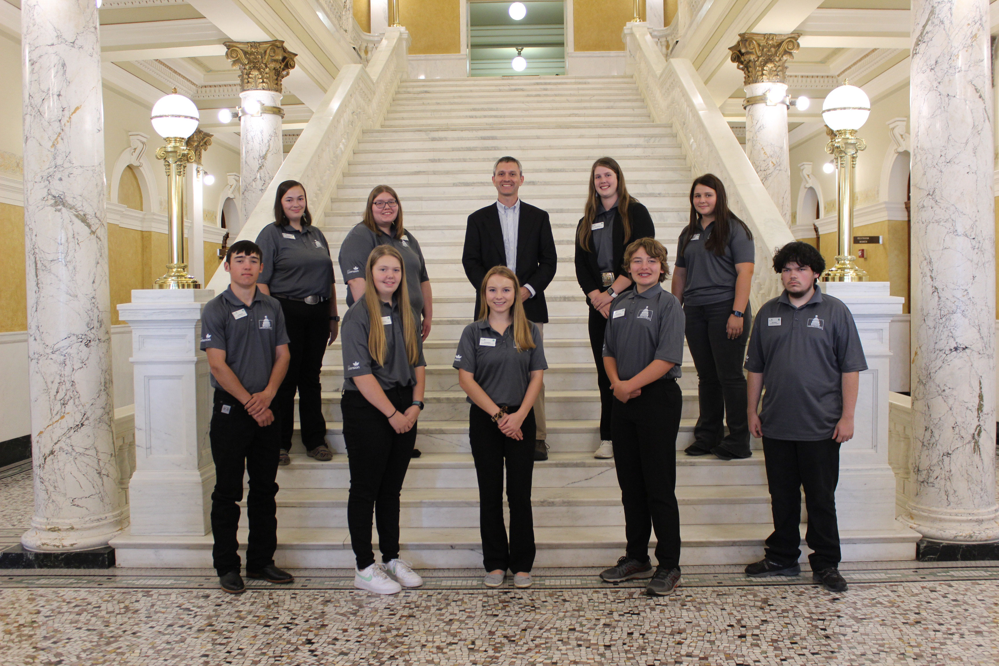 South Dakota 4-H Program Director Tim Tanner with a group of 4-H youth on the grand staircase inside the South Dakota State Capitol.