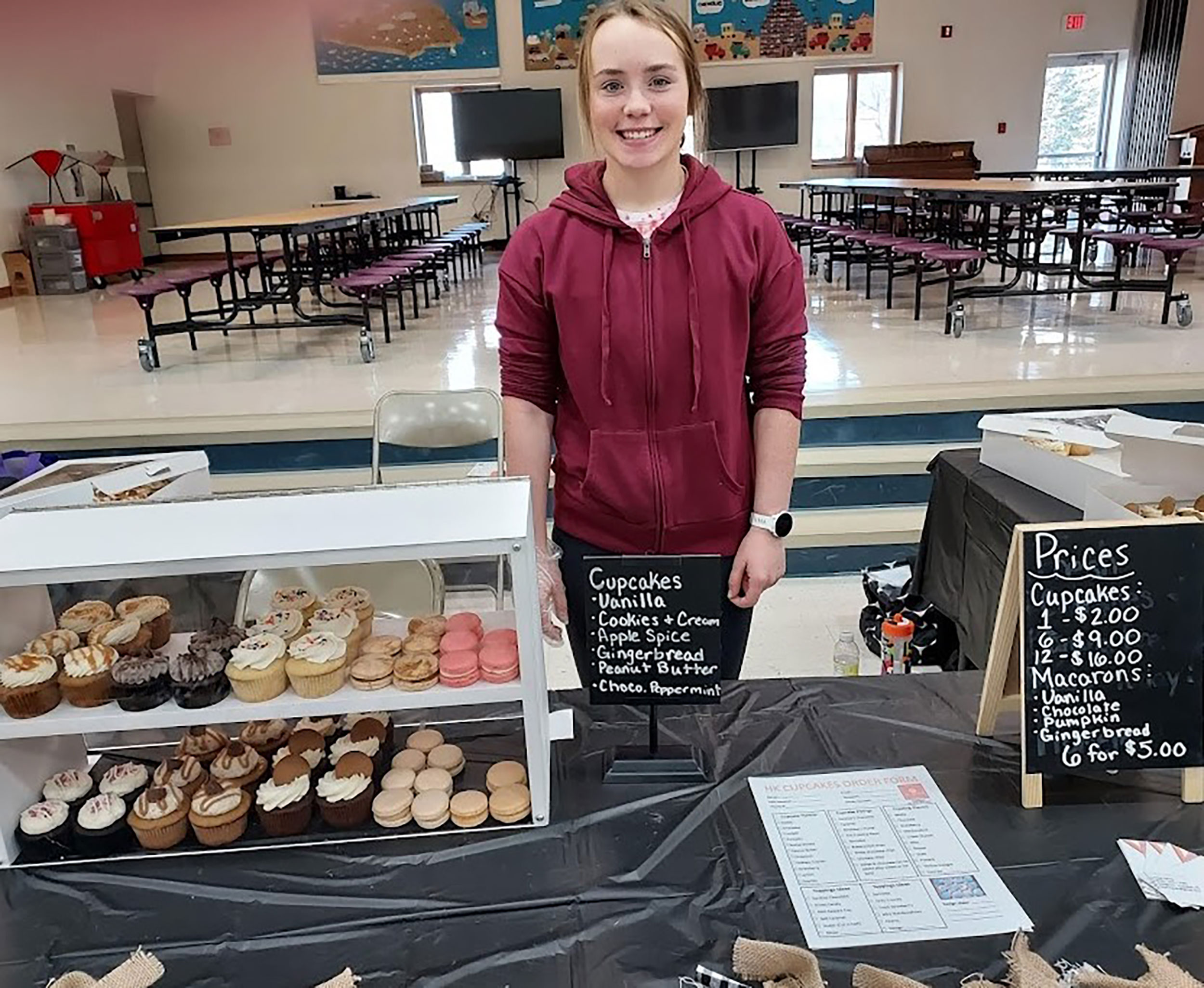 Grant County 4-H member Hope Karels presenting a variety of baked goods for sale in a cafeteria.