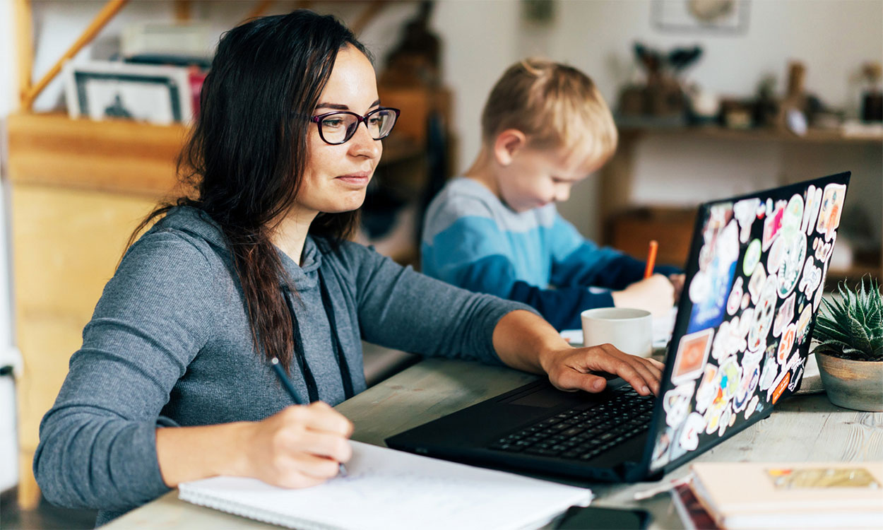 Young mother working remotely on a laptop computer in her kitchen.