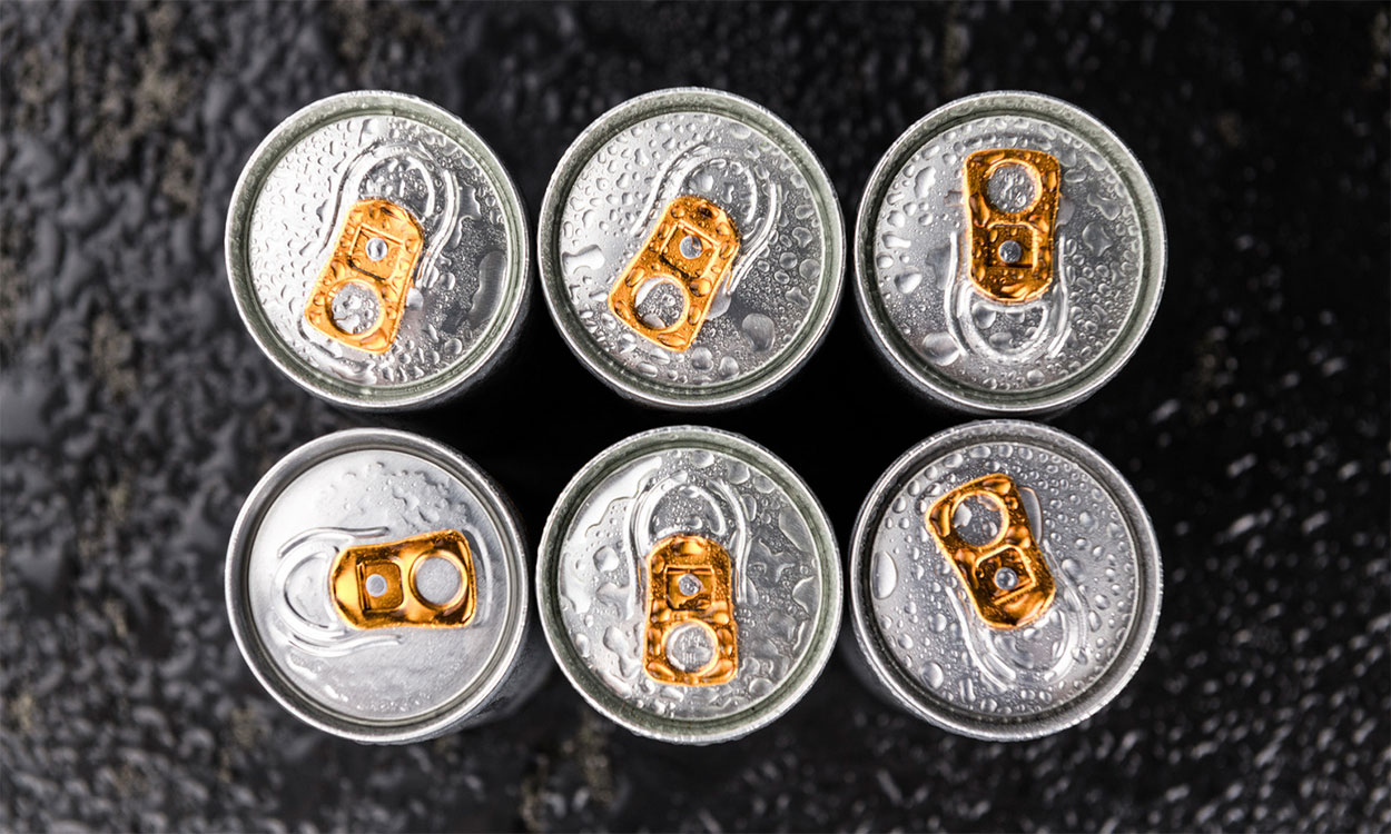 Six canned energy drinks on a dark slate.