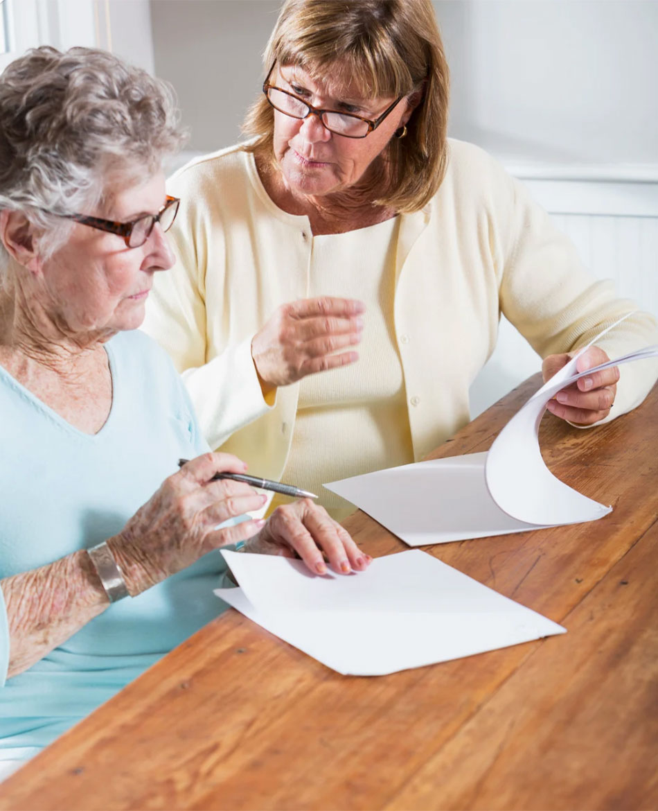 Mother and daughter reviewing paperwork at kitchen table.