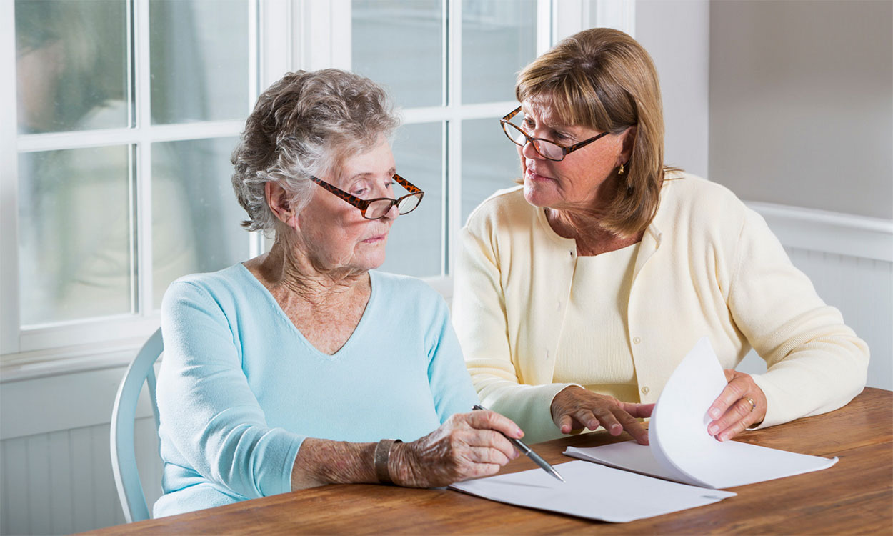Mother and daughter reviewing paperwork at kitchen table.