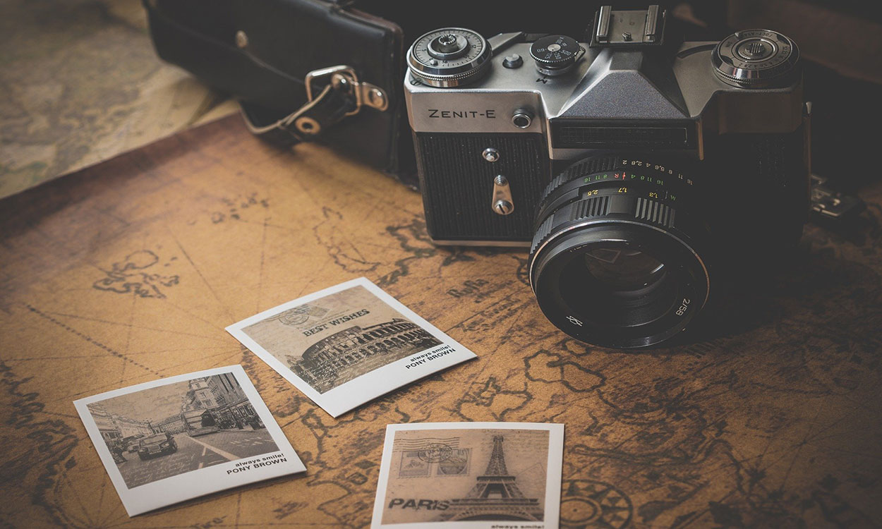 A camera and black and white photos sitting on top of a map.