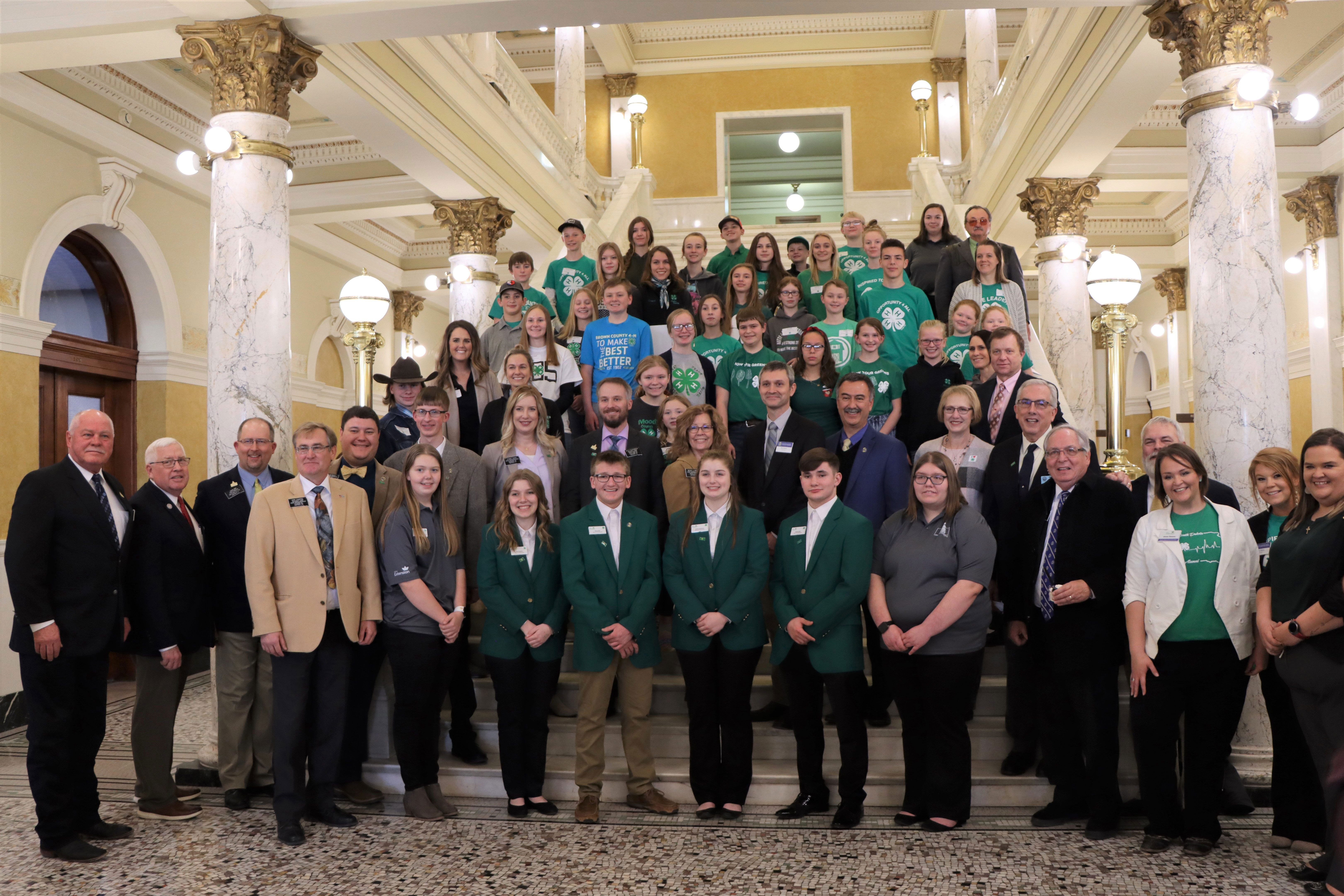 4-H Capitol Day participants stand at the S.D. Capitol building steps with S.D. Senators and Representatives and university personnel.