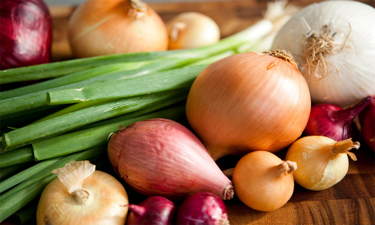 Variety of freshly harvested onions on a cutting board.