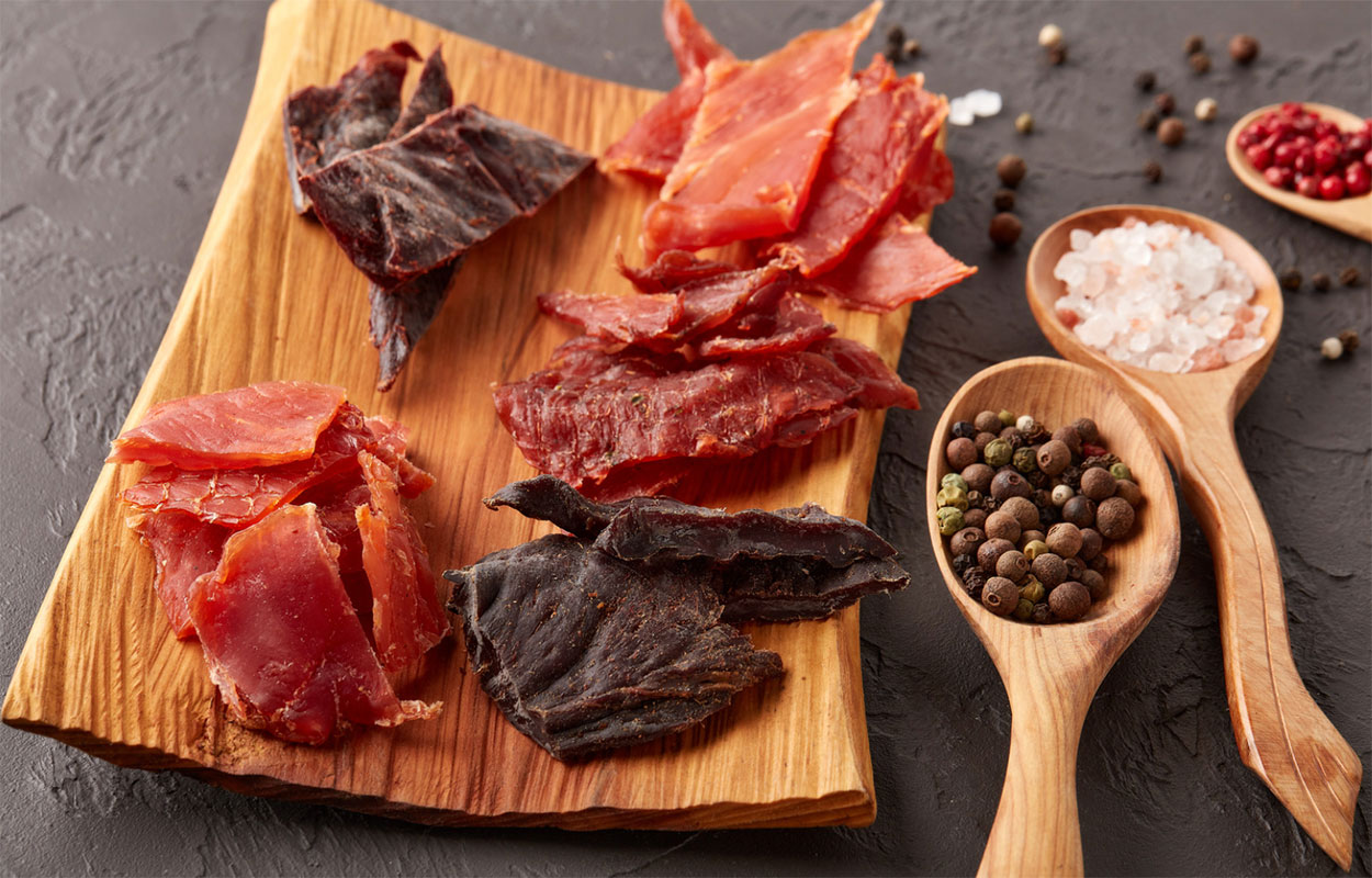 Different types of jerky on a cutting board.