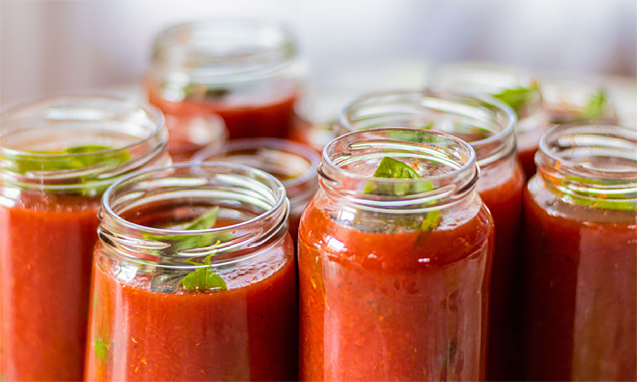 Several canning jars filled with tomato sauce and herbs.