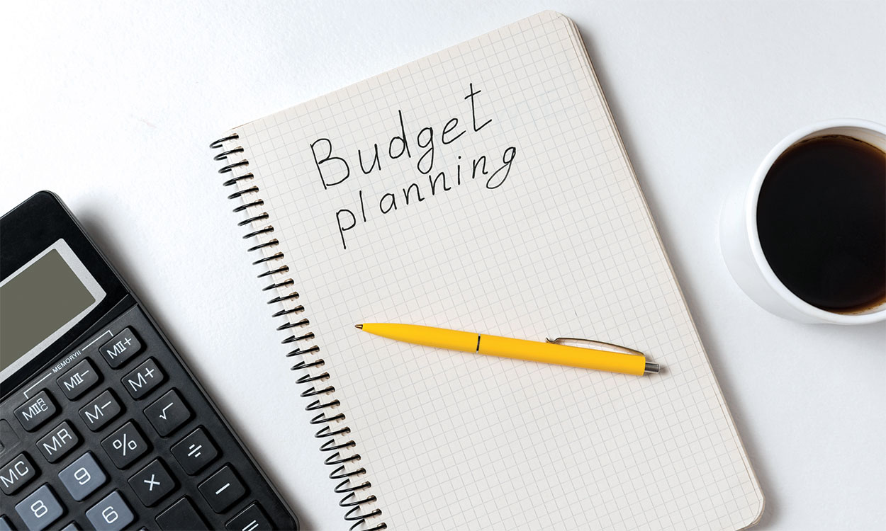 Calculator, pen, and notebook with &quot;Budget Planning&quot; written on it.