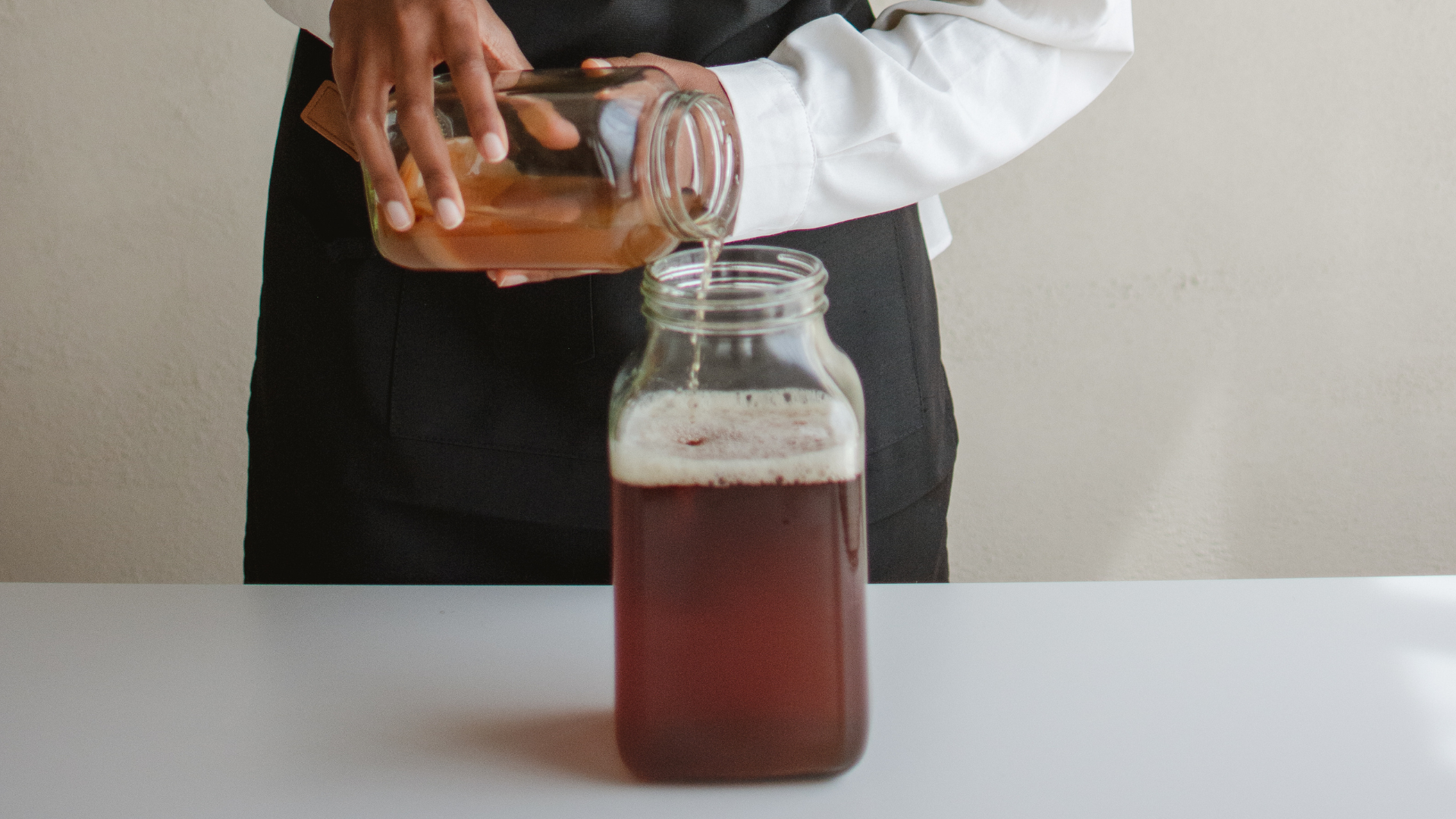 Someone pouring tea from one jar to another