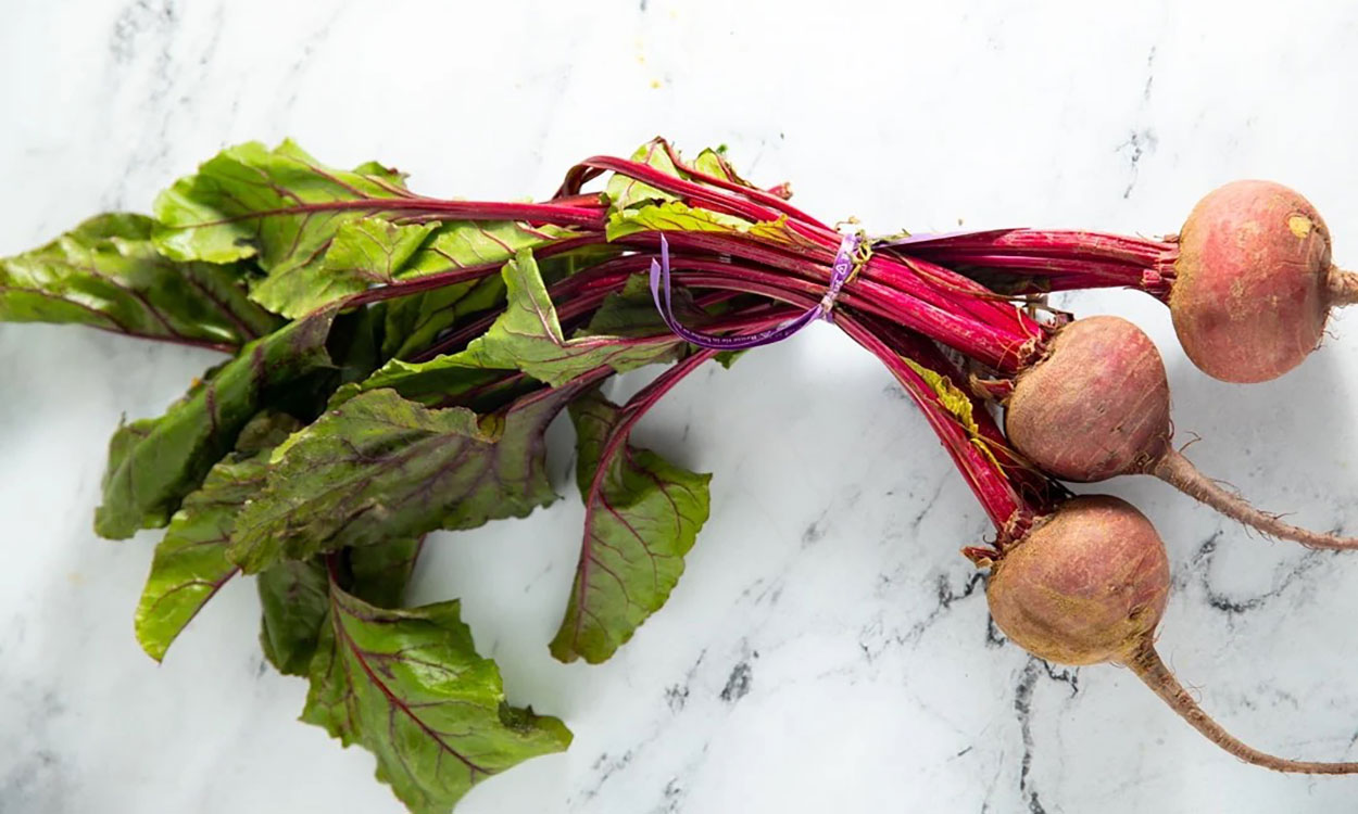 Three beets harvested and bunched together with greens intact.