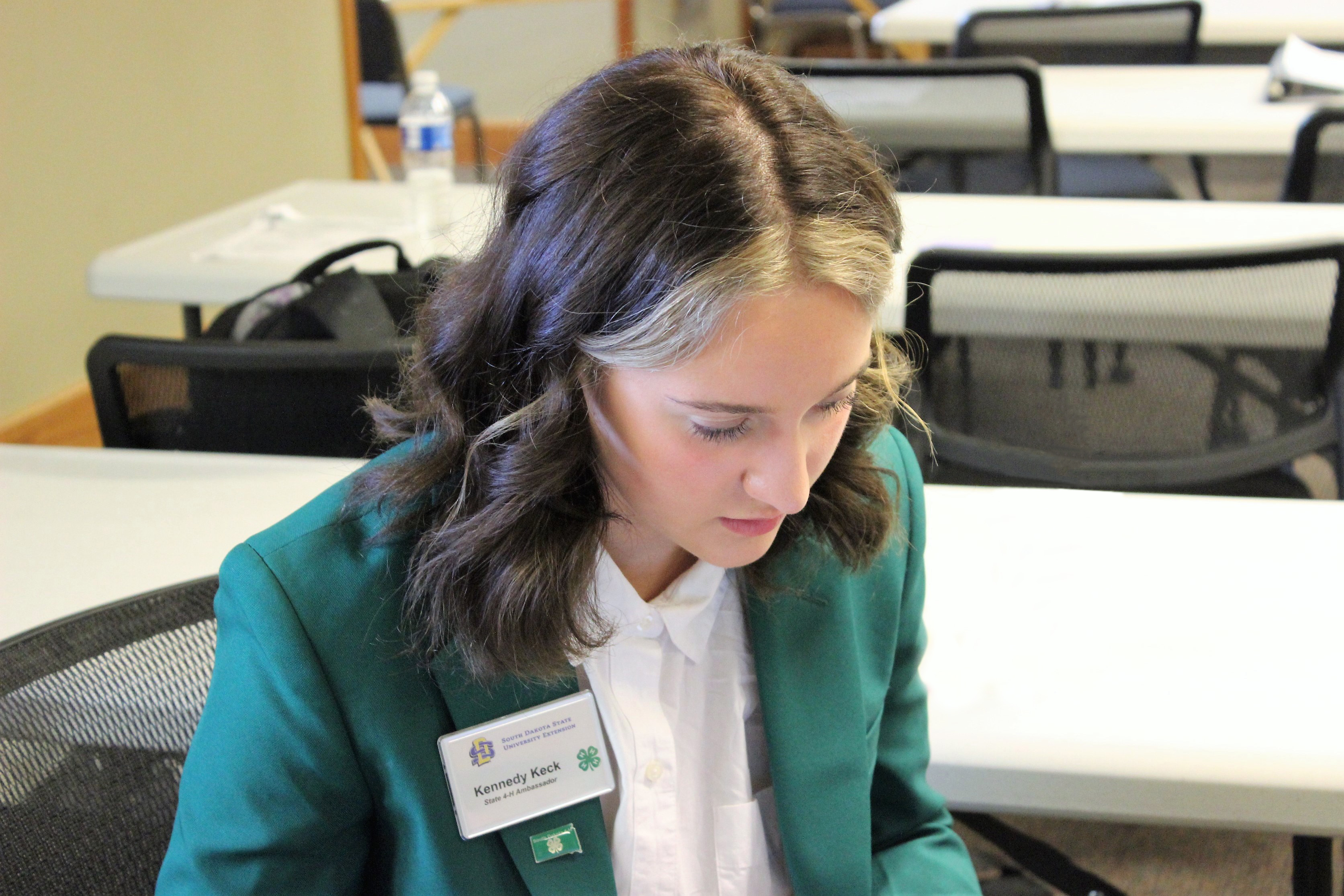 State 4-H Ambassador sitting at a table filling out an application
