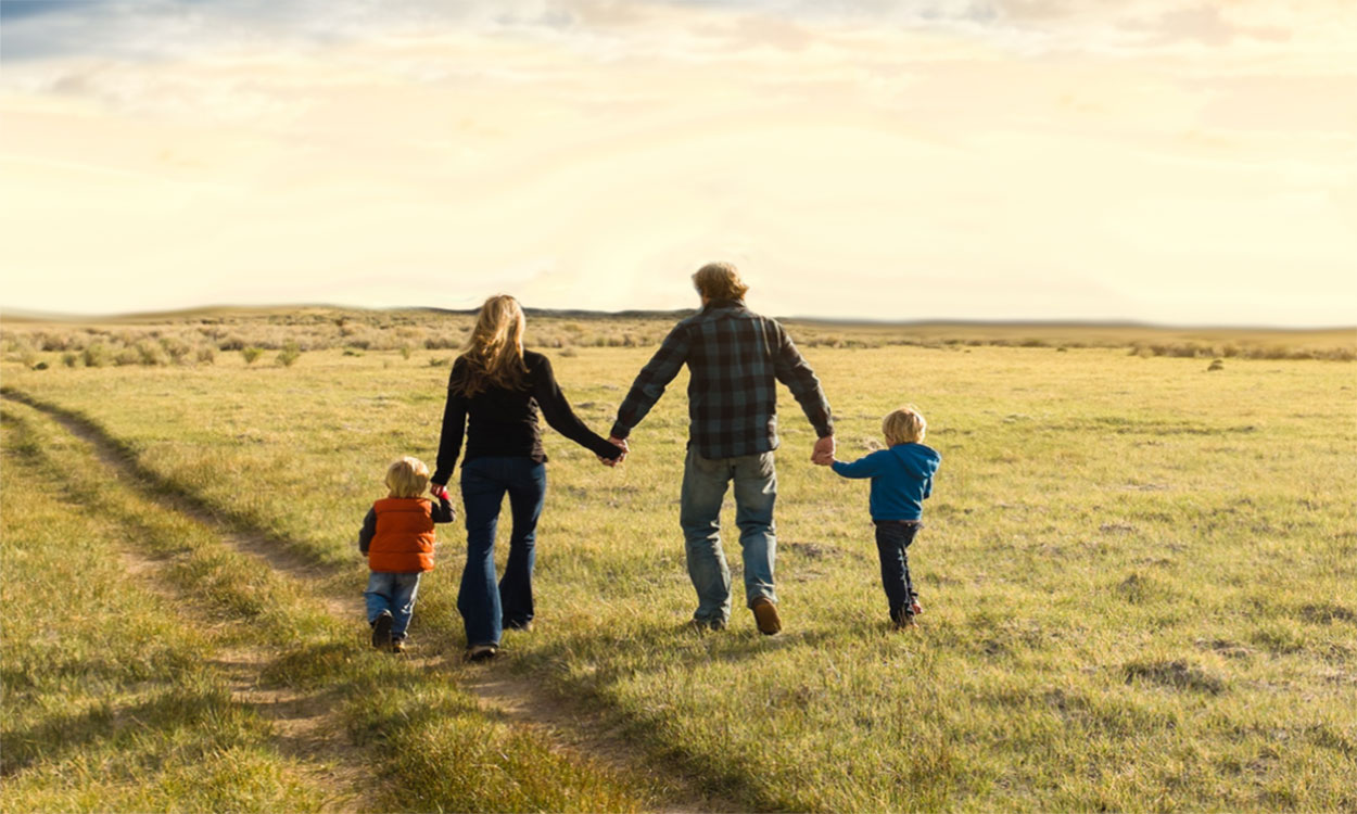 Family walking in an open, country field.
