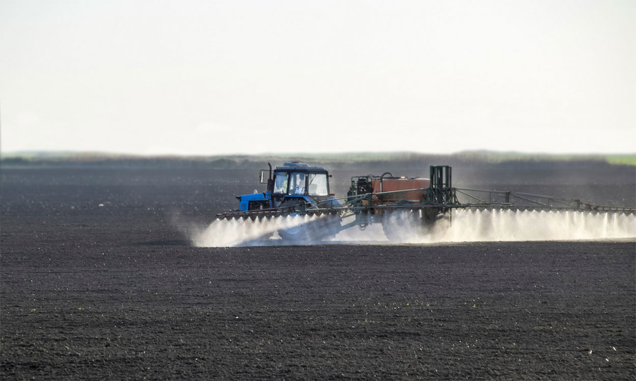 Tractor applying preemergence herbicide on a freshly planted field.