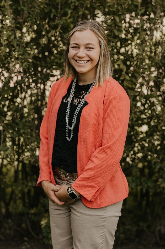 Abbi Steeke stands outside in front of a bush