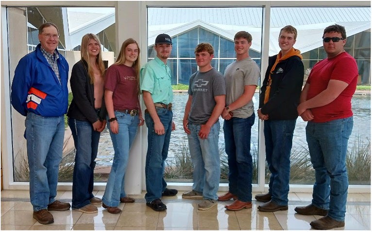 The Day County 4-H and Webster FFA Range Judging teams stand in a row in front of a window.
