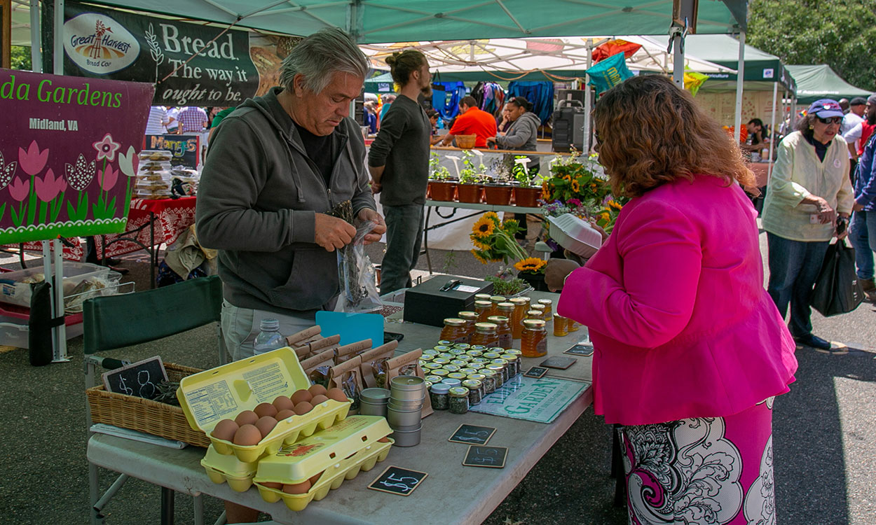 Vendor selling a variety of food products at a farmer’s market.