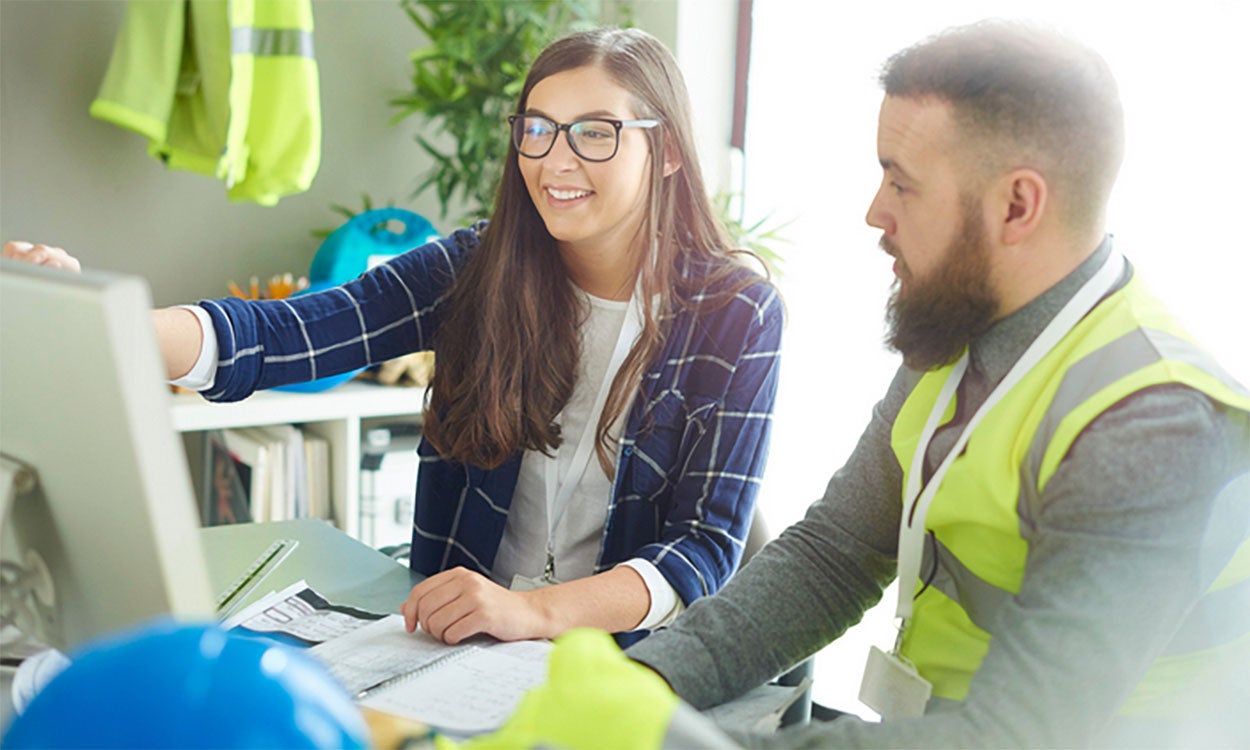 Public service worker sitting at a computer with a construction worker.