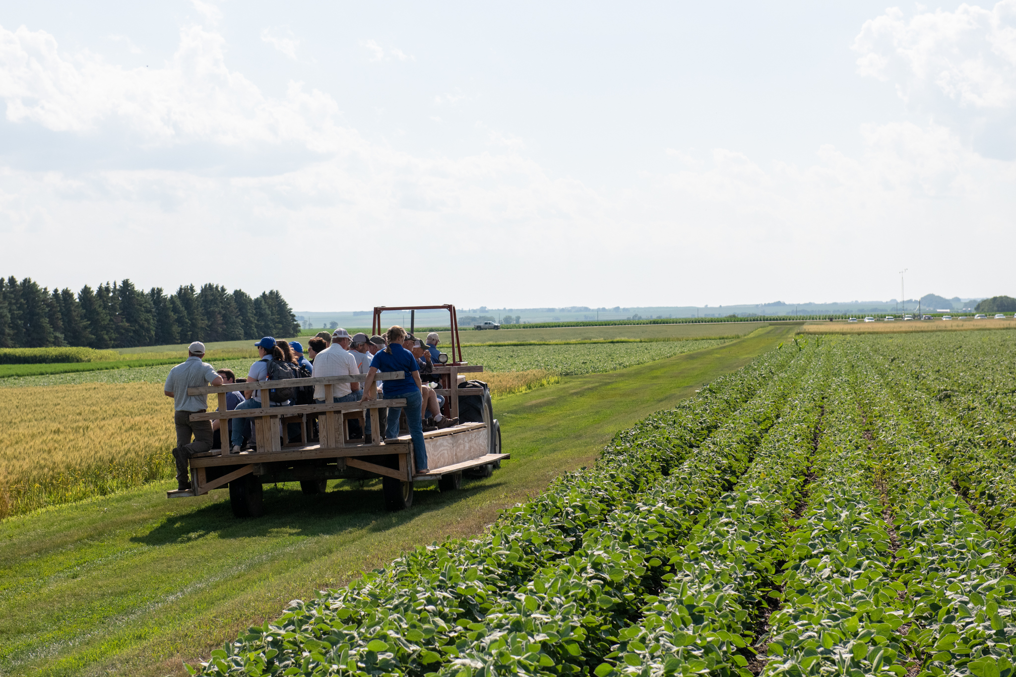 A group of people rides on a trailer through the Northeast Research Farm