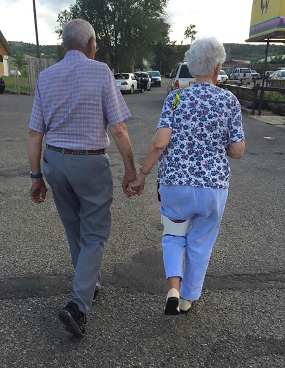 Two older adults holding hands while walking.